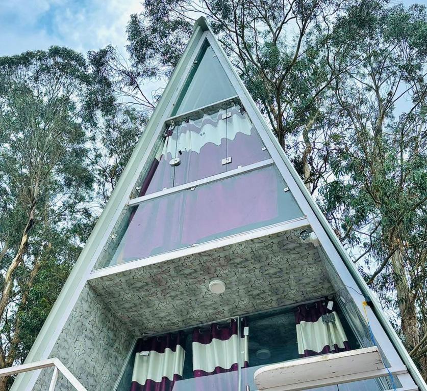 una casa a forma di piramide con una finestra e alberi di D Classicals a Kodaikānāl