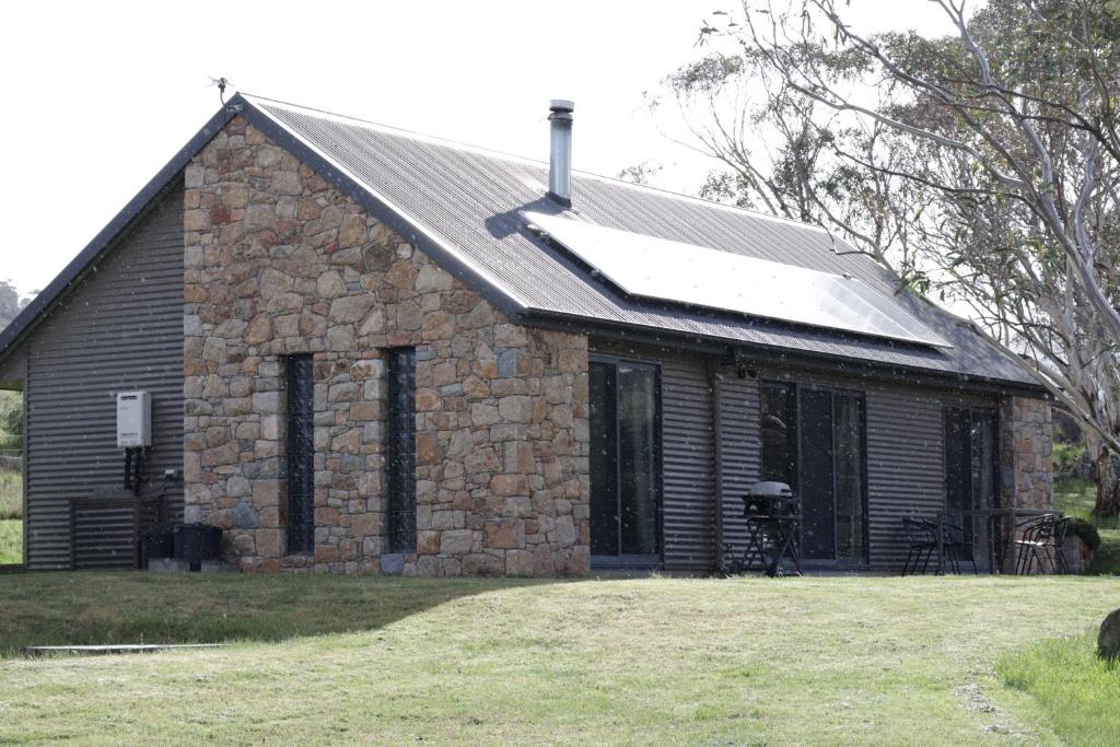 un edificio in pietra con un tetto e una finestra di Emu Rest Touchdown Cottages a Jindabyne