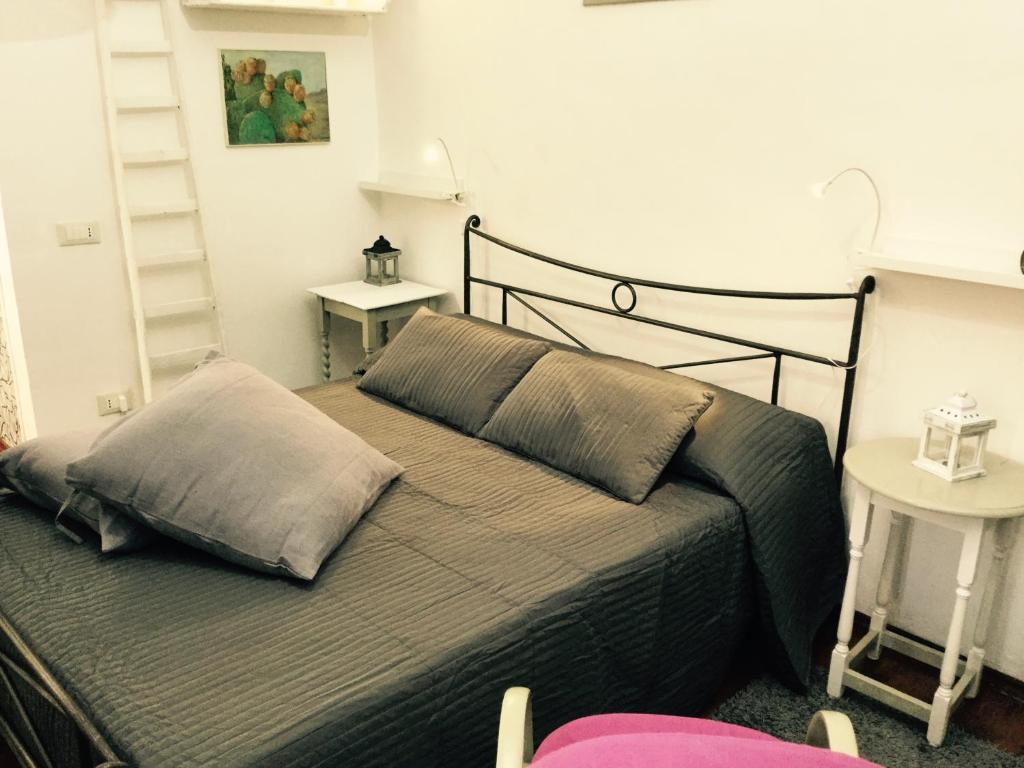 um quarto com uma cama com um cobertor cinzento e duas mesas em Your Home in Town em Catânia