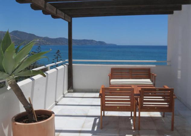 a balcony with two benches and a table and chairs at Fuentes de Nerja in Nerja