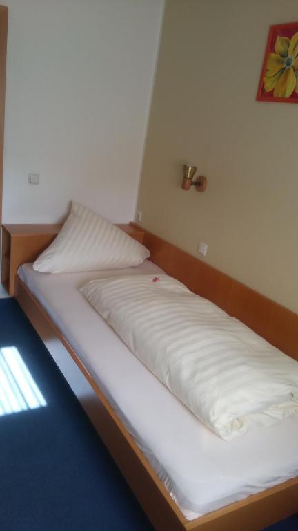 Bett in einem Zimmer mit weißer Bettwäsche in der Unterkunft Landgasthof & Hotel "Merje" in Kreuztal