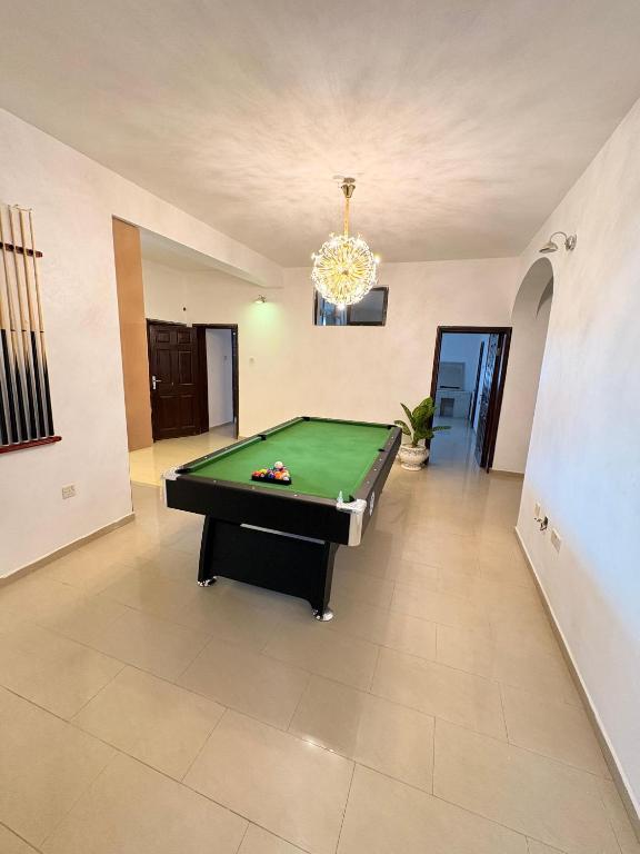 a living room with a pool table and a chandelier at Ishas Apartment in Kusafe