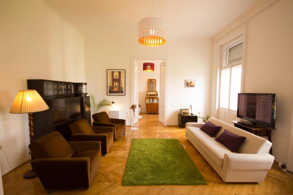 a living room with a couch and chairs and a tv at Arena Apartment in Budapest