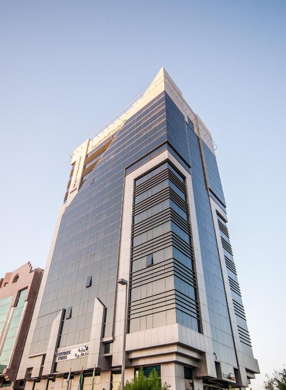 a tall glass building with a blue sky in the background at Executive Suites Abu Dhabi in Abu Dhabi