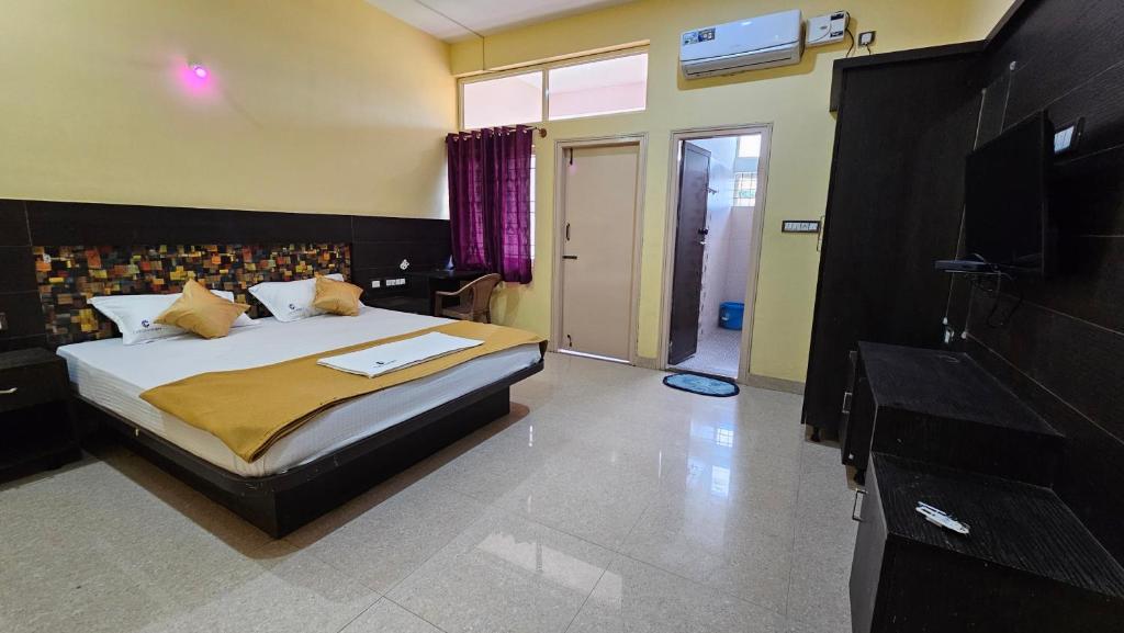 een slaapkamer met een bed en een televisie in een kamer bij Corcordium by ssr in Bilikere