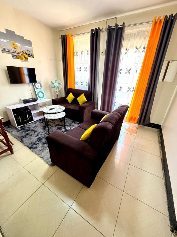 - un salon avec un canapé brun et des oreillers jaunes dans l'établissement House of Hera, à Kisumu