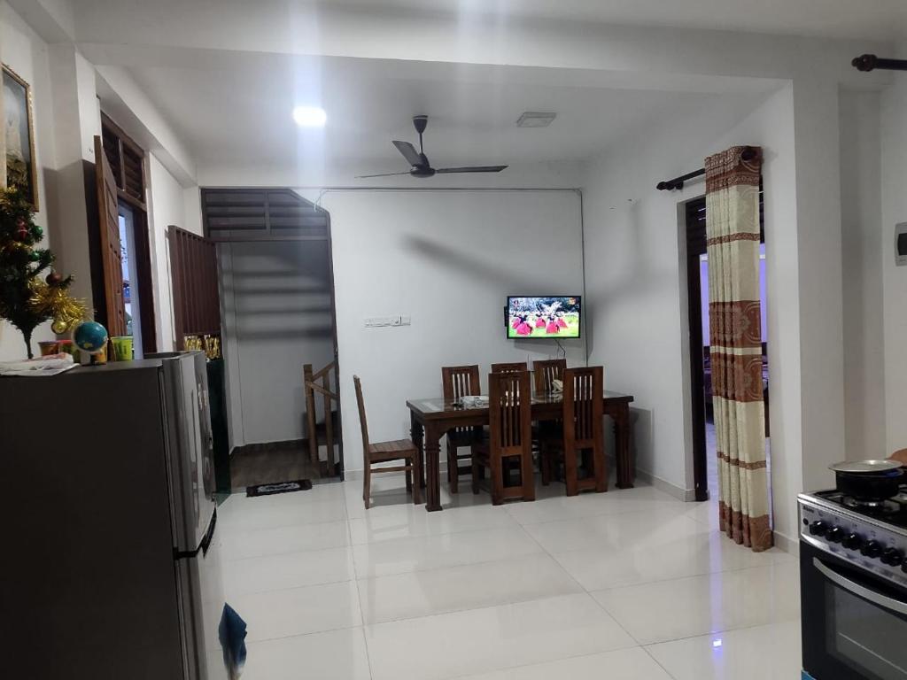 een keuken en eetkamer met een tafel en een tv bij Prince House in Piliyandala