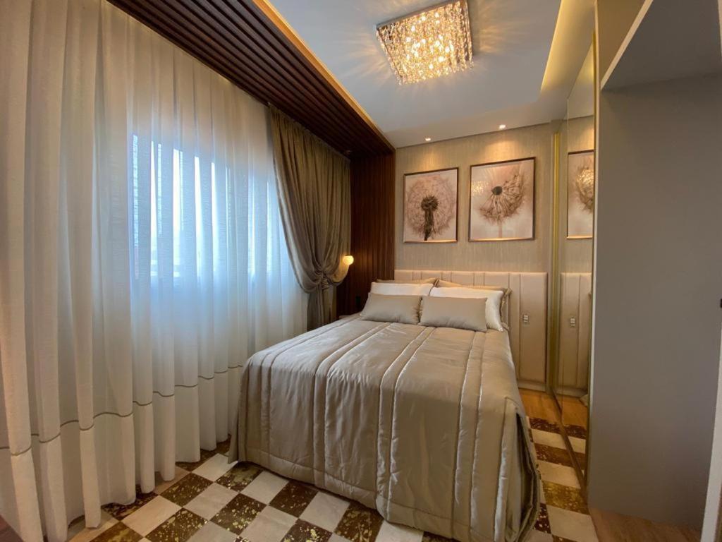 ein Schlafzimmer mit einem Bett und einem großen Fenster in der Unterkunft Apartamento Vó Lêla in Bombinhas