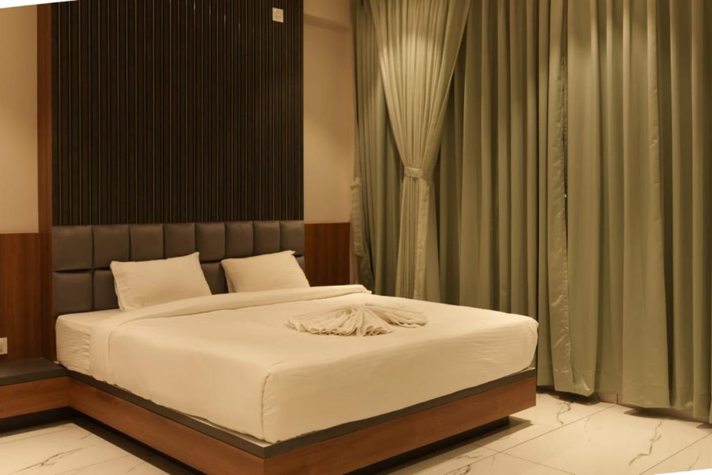 een slaapkamer met een bed met witte lakens en gordijnen bij HariPriya Executive in Tuljapur