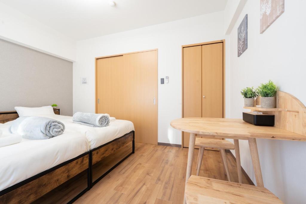 um quarto com uma cama e uma mesa de madeira em Bloomsbury 402 em Wada
