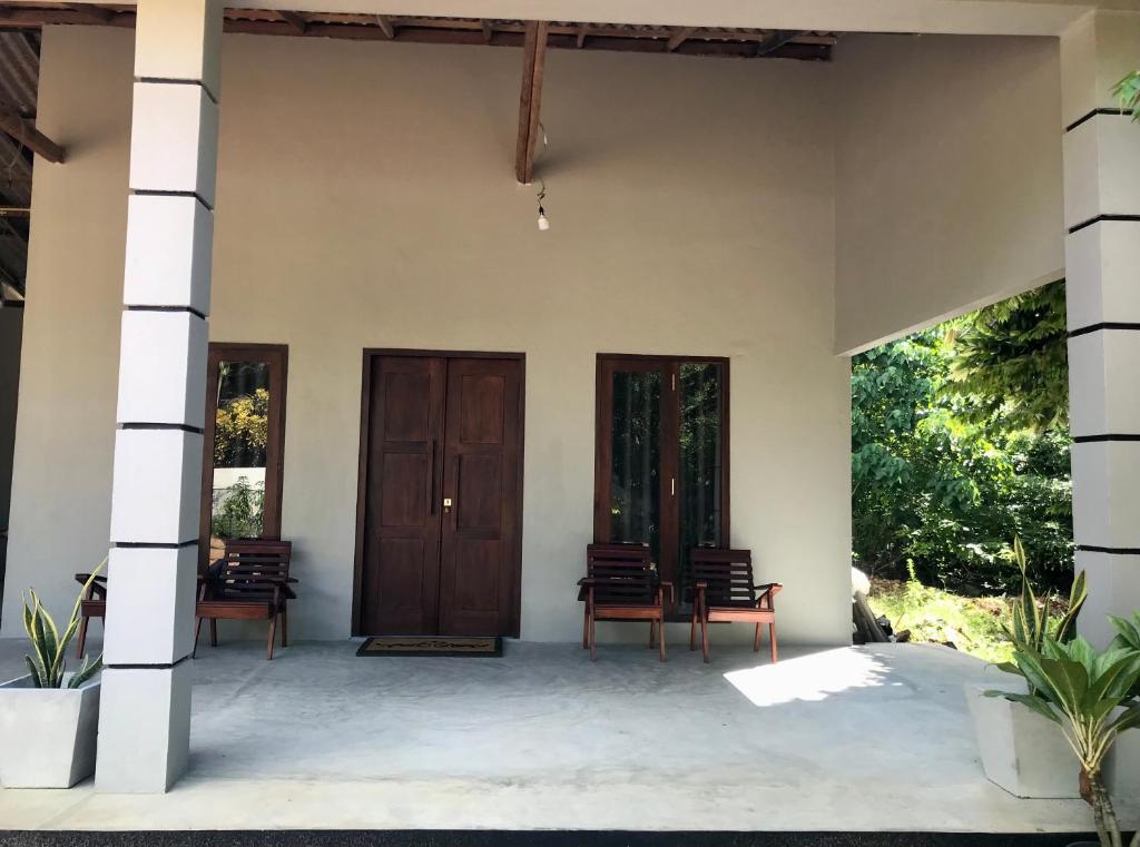 a porch of a house with wooden doors and chairs at Amelia Villa in Gandara West