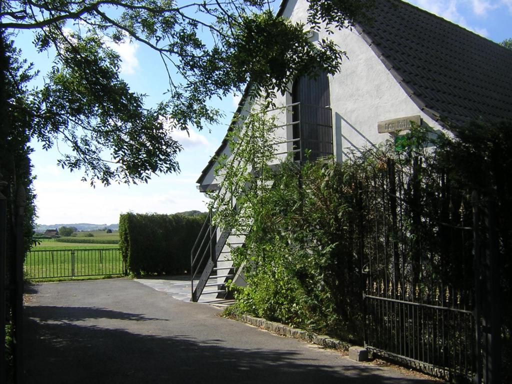 uma casa com uma cerca e uma escada ao lado de um edifício em The Cosy Hill em Poperinge