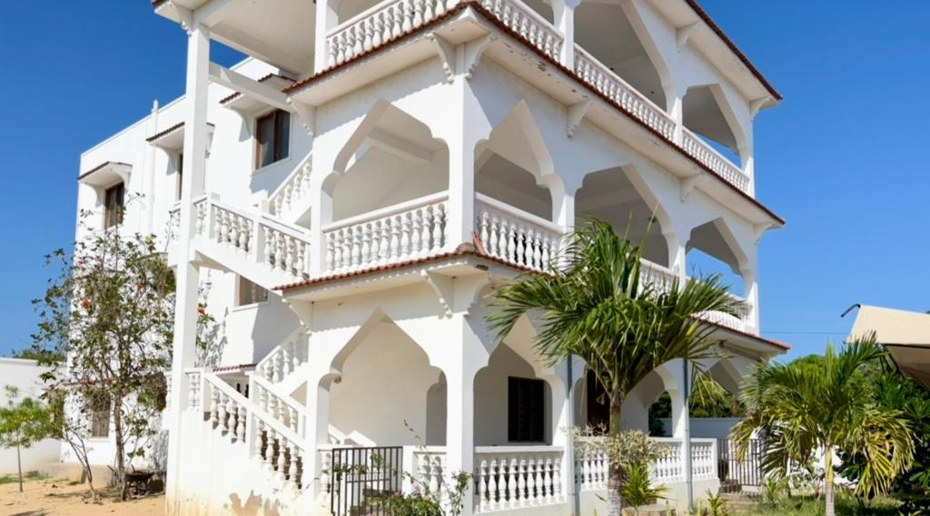 een wit gebouw met witte balkons en palmbomen bij Diamond Luxury Homes in Watamu