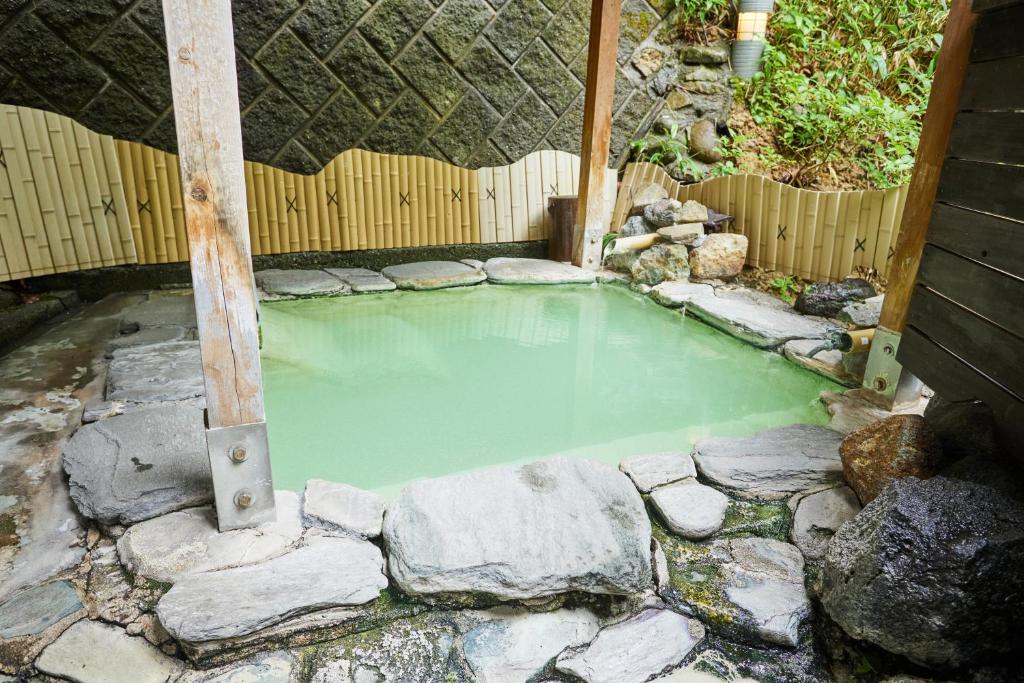 uma piscina de água verde com pedras ao redor em ゆのホテル奥日光やまみず樹 em Yumoto