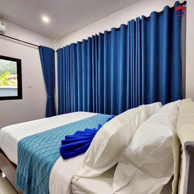 a bedroom with a bed with blue curtains at Aqua Pool villa, Krabi in Ban Nong Thale