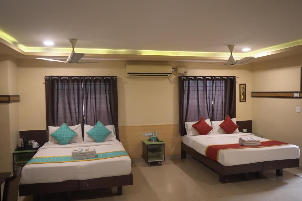 a hotel room with two beds with red and blue pillows at Hotel UR Comforts Jayanagar in Bengaluru