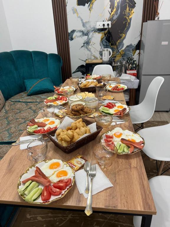 にあるUsman Guesthouseの食べ物の皿が置かれた木製のテーブル