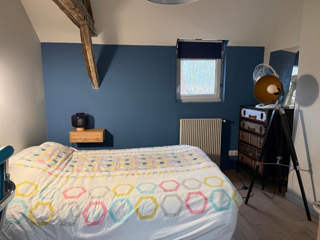 a bedroom with a bed and a blue wall at La chambre du Parc in Amiens
