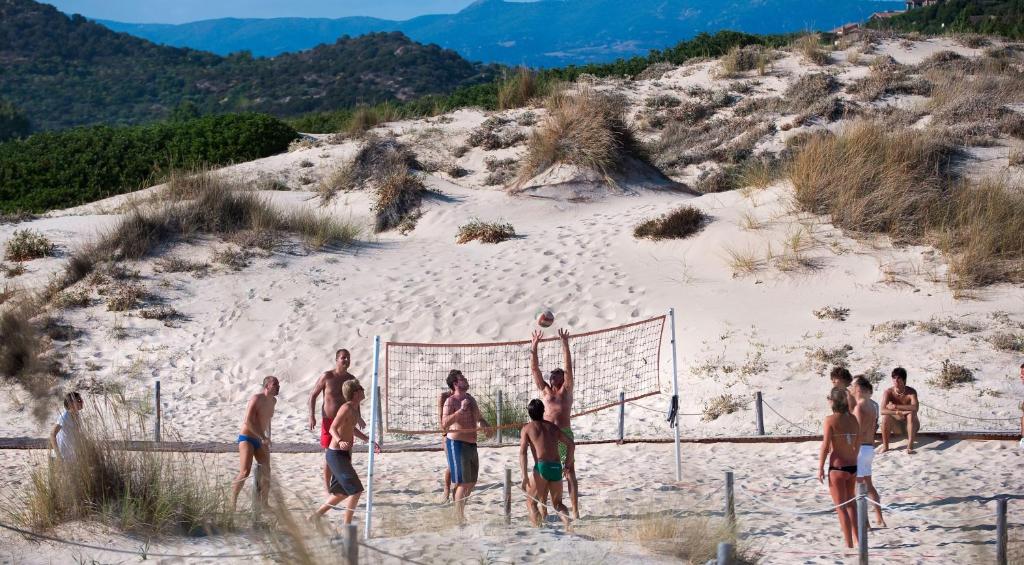 a group of men playing volleyball on a beach at Chia Laguna - Hotel Village in Chia