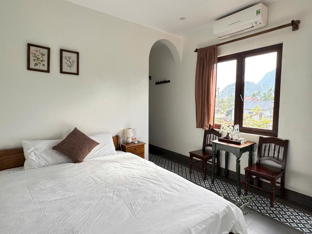 Un dormitorio con una cama y una ventana y una mesa. en Anio Ha Giang Hotel, en Ha Giang