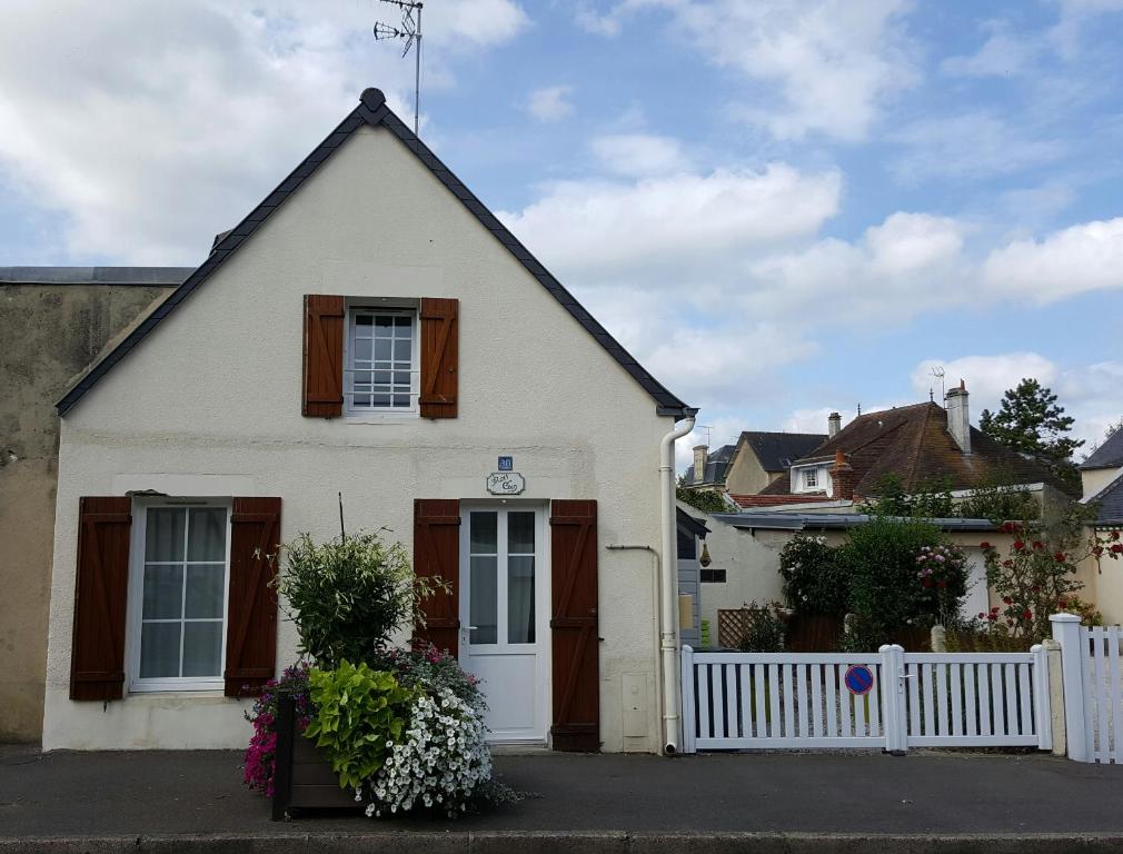 una casa bianca con una recinzione bianca davanti di Maisoun Pequeux ad Arromanches-les-Bains