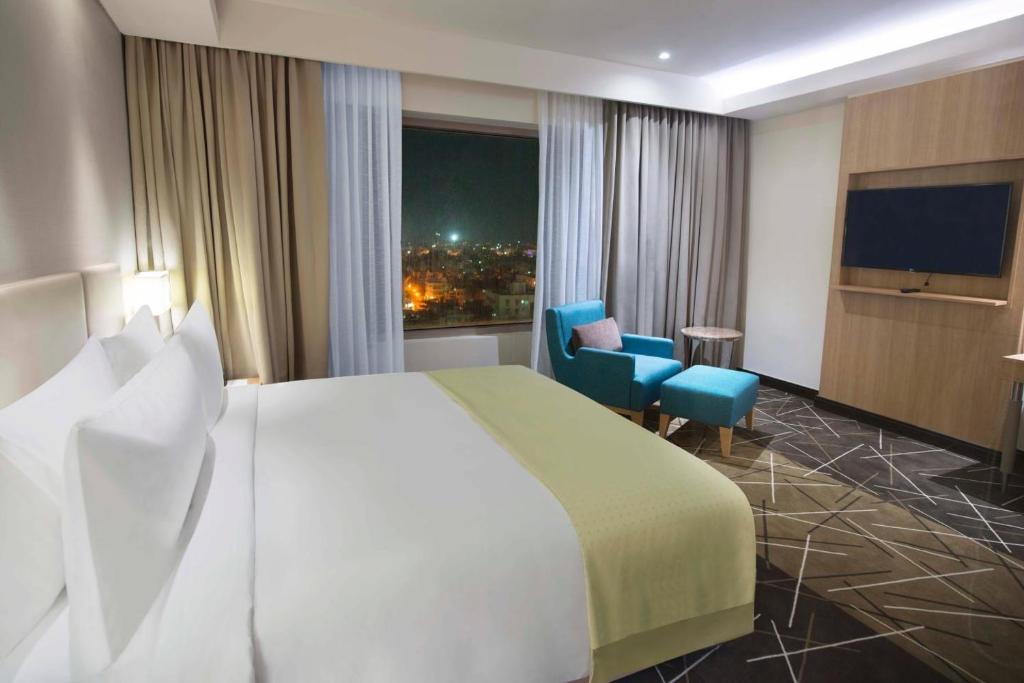 ニューデリーにあるHotel Jupiterのベッドと大きな窓があるホテルの部屋