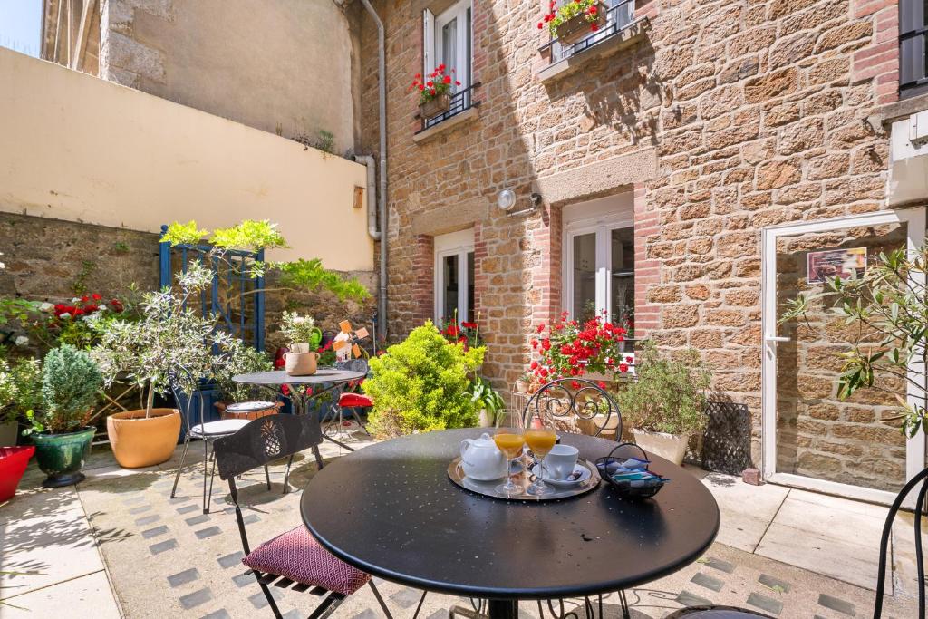 Un patio con mesa y sillas y un edificio. en Hôtel Quic en Groigne, en Saint-Malo