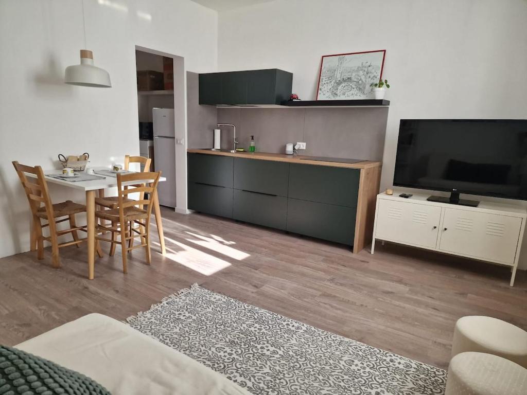 a living room with a kitchen with a table and a television at Trento Living in Trento