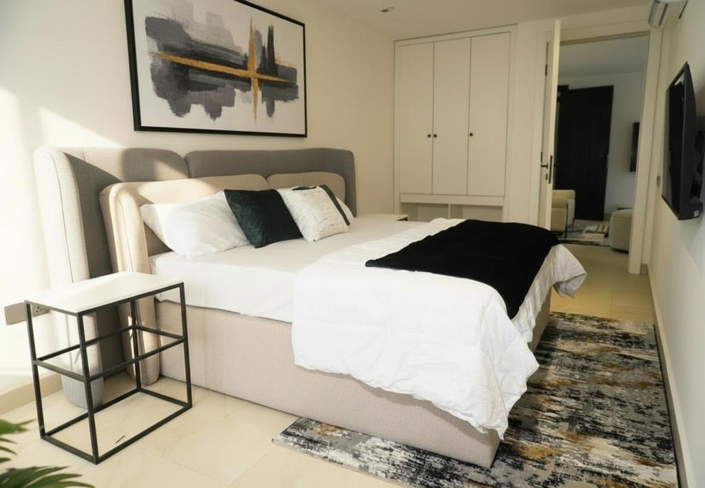 un dormitorio con una cama con sábanas y almohadas blancas en The Estoria Lagos, en Ikeja