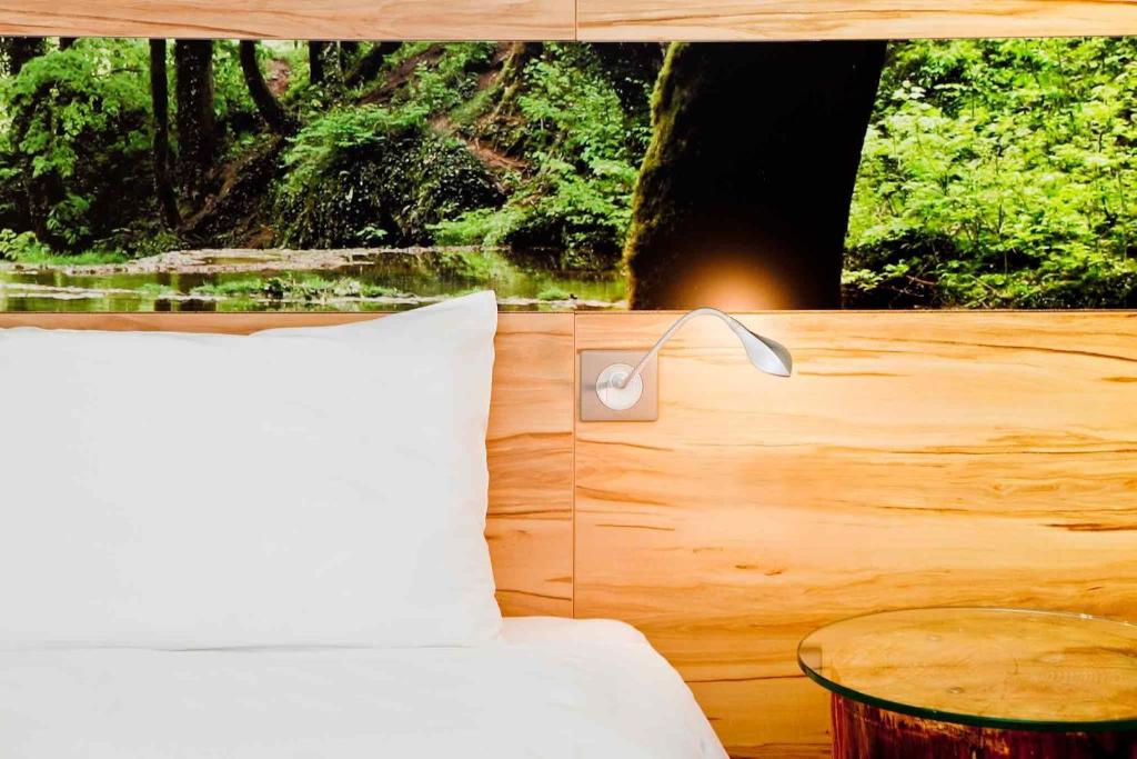 ibis Styles Sarrebourg في ساريبورج: غرفة نوم بسرير مع طاولة ومصباح