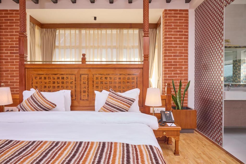 um quarto com uma cama grande e uma parede de tijolos em Soaltee Westend Resort Nagarkot em Nagarkot