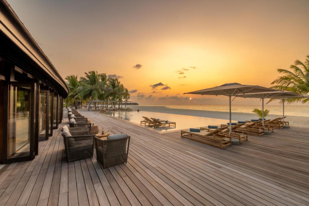 una passerella con sedie e ombrelloni su una spiaggia di Nala Maldives by Jawakara ad Atollo Lhaviyani