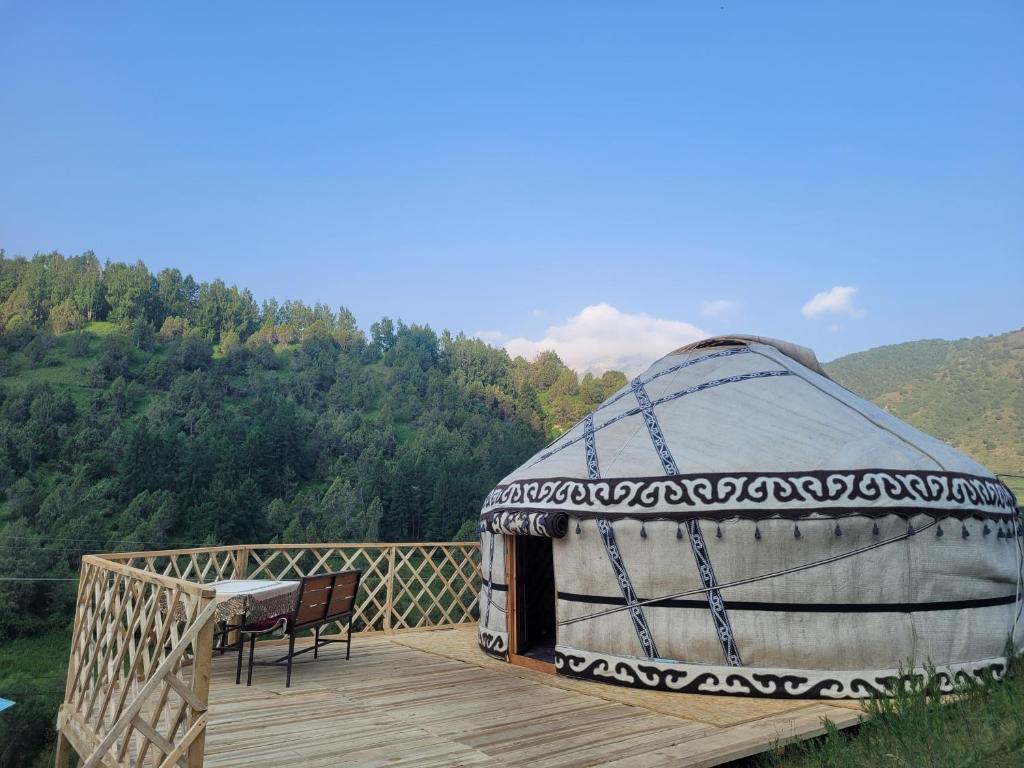 een yurt met een tafel en een stoel op een houten terras bij Maksyt Ata Hostel in Kalday