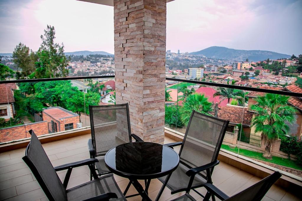 einen Balkon mit 4 Stühlen und einem Tisch mit Aussicht in der Unterkunft Agasaro House Kigali in Kigali