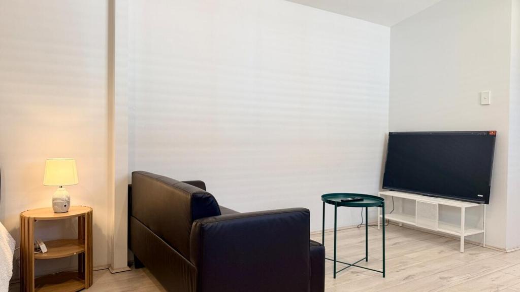 ein Wohnzimmer mit Sofa und Fernseher in der Unterkunft Private Granny Flat Studio in Chatswood in Sydney