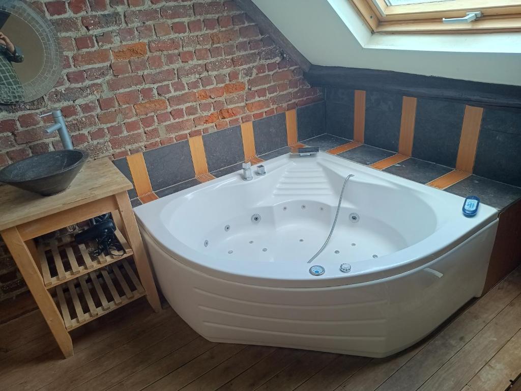 a large white bath tub in a room with a brick wall at Cheap hotel near Brussels airport in Kortenberg