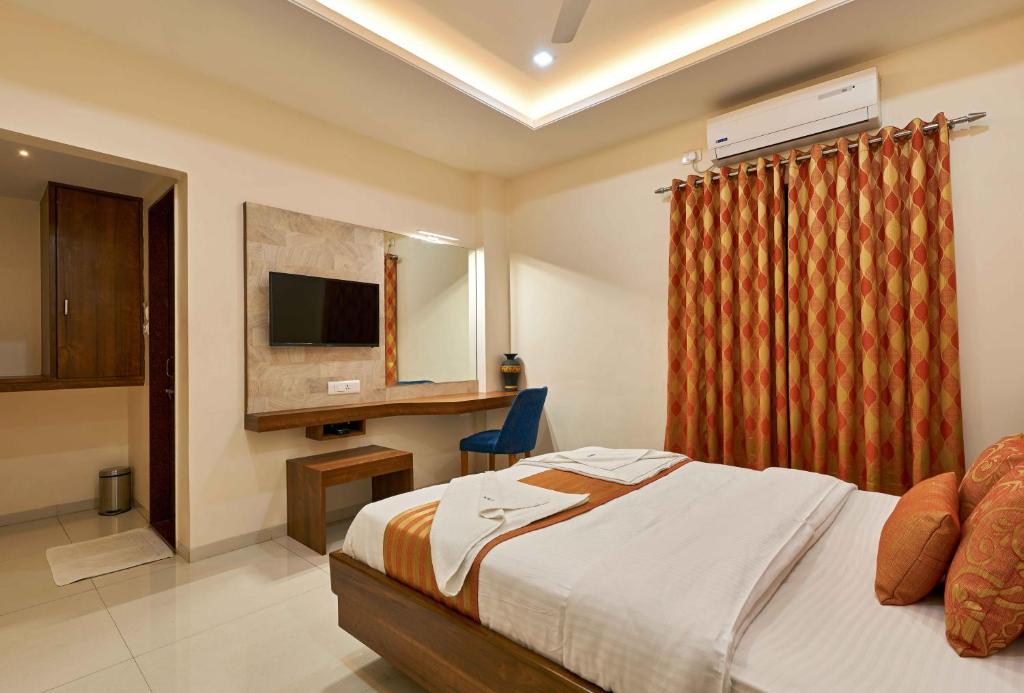 a bedroom with a bed and a desk and a television at Hotel Rajpurush in Kolhapur