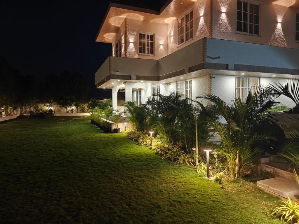 a house with lights on the lawn at night at Palms Villa in Dharmpura