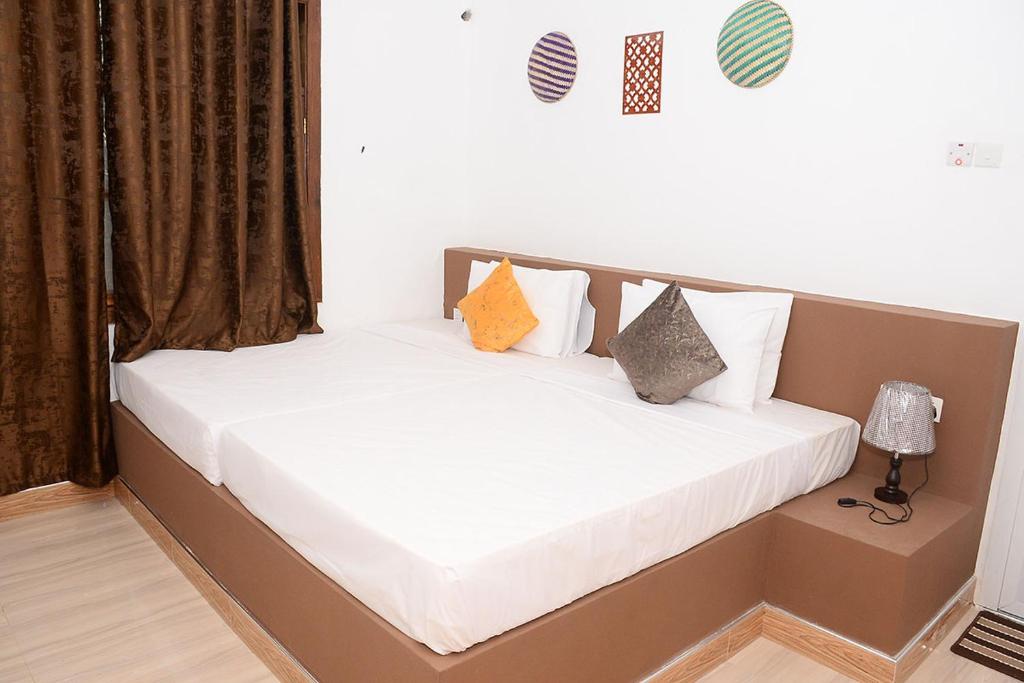 Un dormitorio con dos camas con sábanas y almohadas blancas. en Mbilimbi Malazi, en Zanzíbar