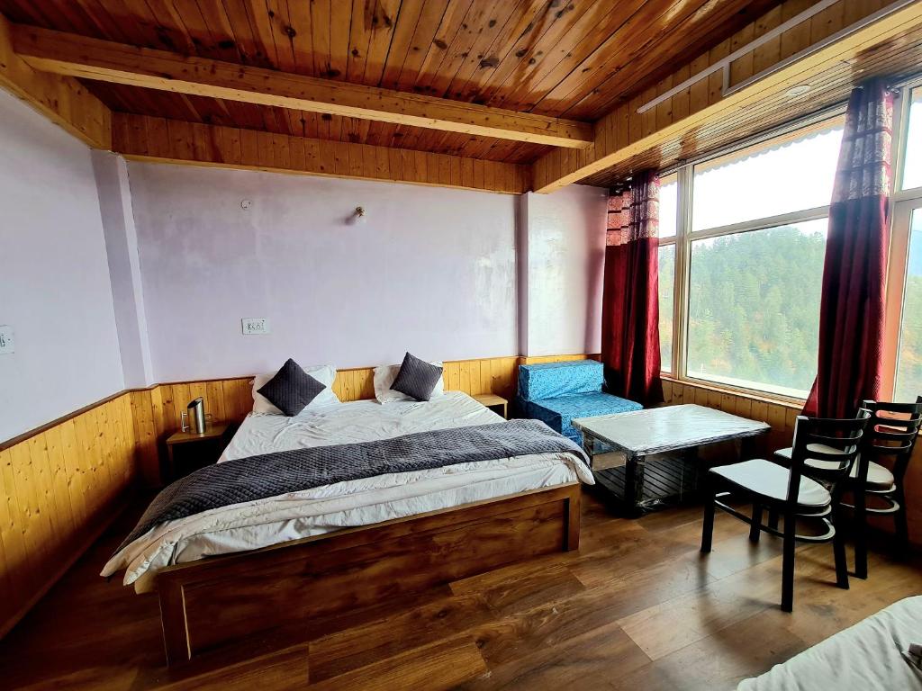 a bedroom with a bed and a table and a window at Narkanda Heights Rooms in Nārkanda
