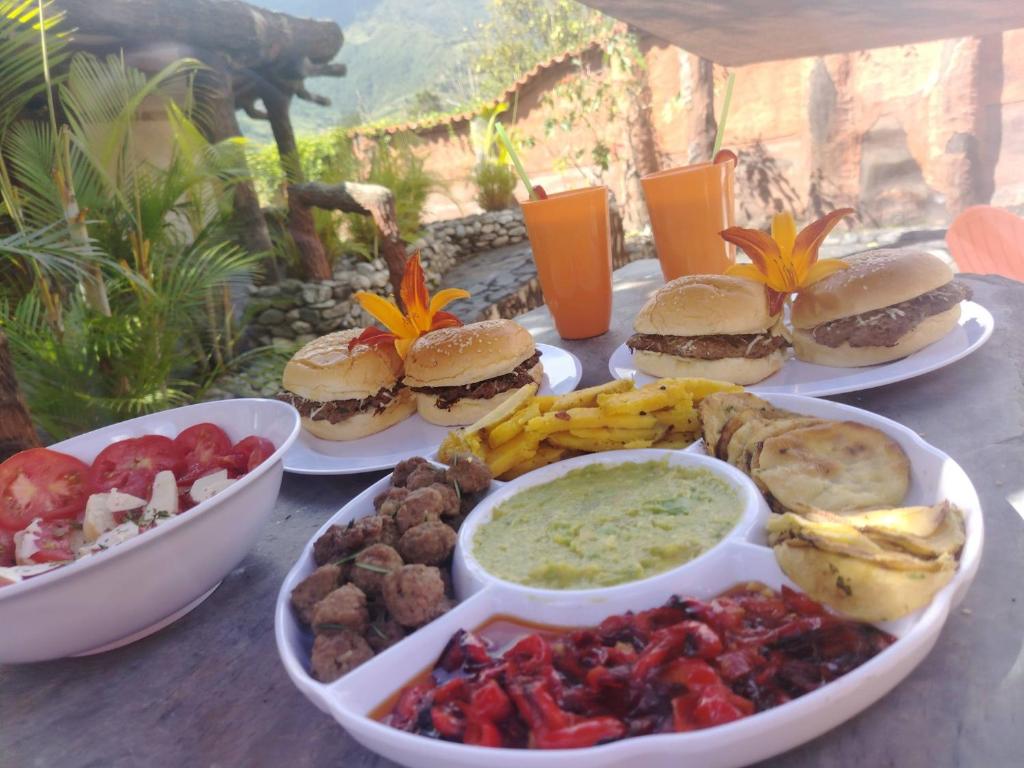 un tavolo sormontato da piatti di cibo con hamburger e salse di Bella Vista Suites Mérida a Tabay