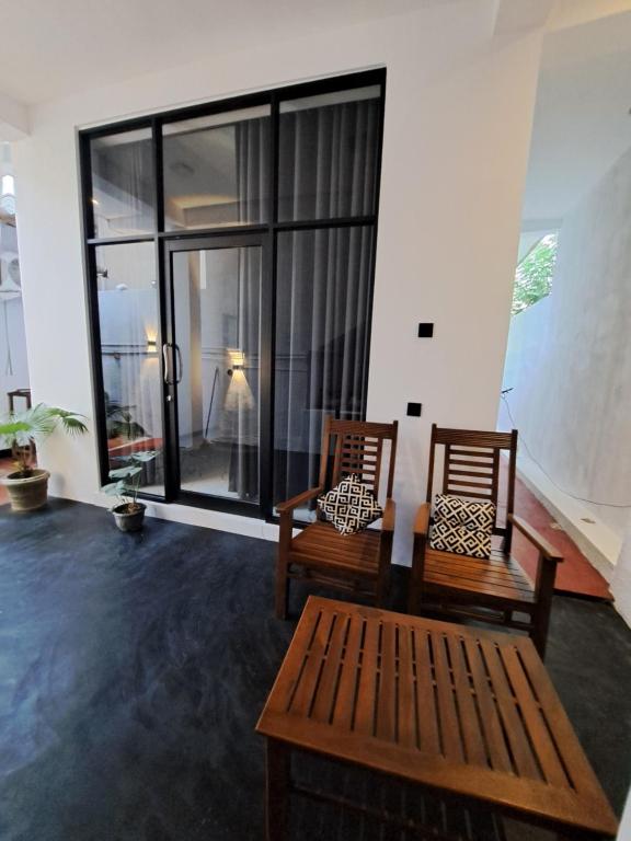 two chairs and a bench in a room with large windows at Kavidi Villa Home Stay in Tangalle
