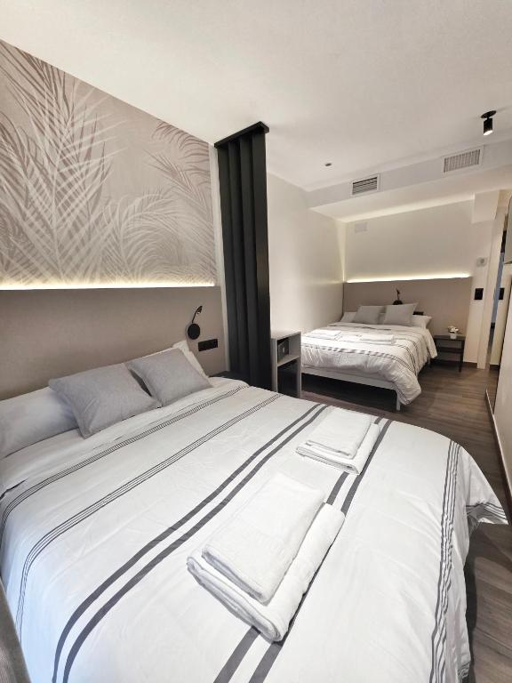 a bedroom with two beds with white sheets at Pension Oasis Alicante in Alicante