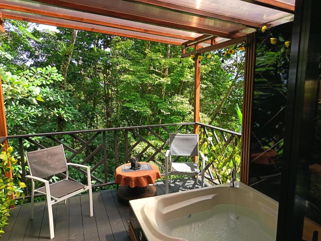 a tub on a deck with two chairs and a table at Breezes Ecolodge in San Ramón
