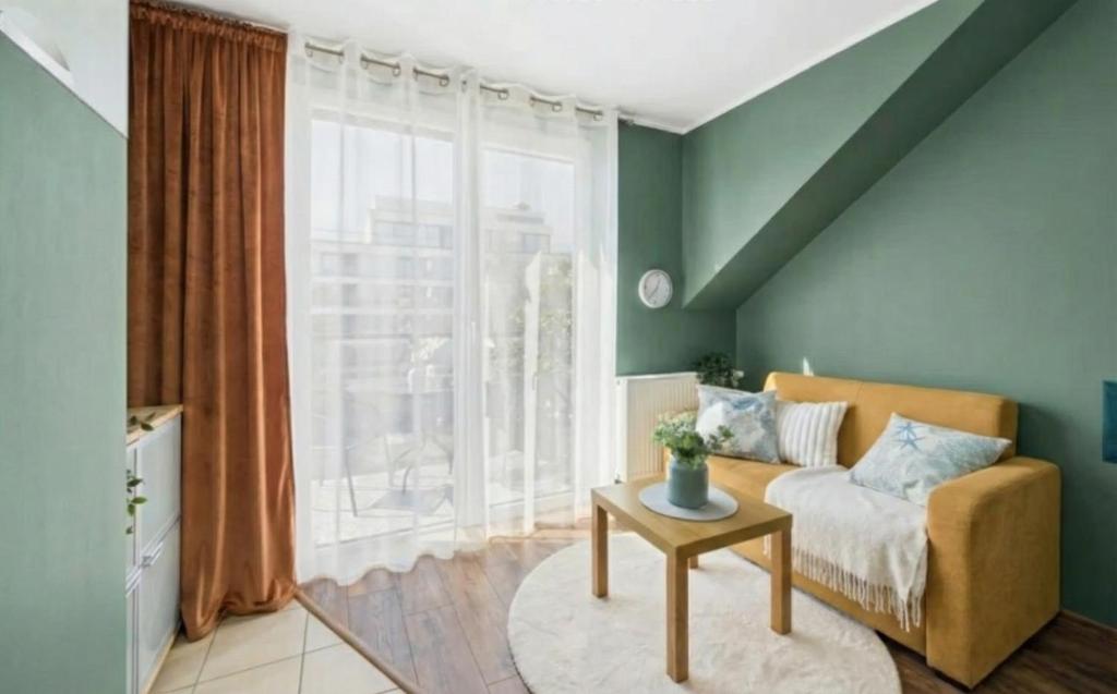 een woonkamer met een bank en een groot raam bij Sunny Tides in Mielno