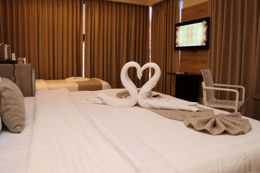 twee witte zwanen maken een hart op een bed bij ALENA HOTEL in Aqaba