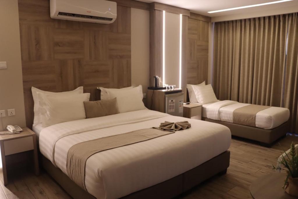 Una habitación de hotel con dos camas y una ventana. en ALENA HOTEL, en Áqaba