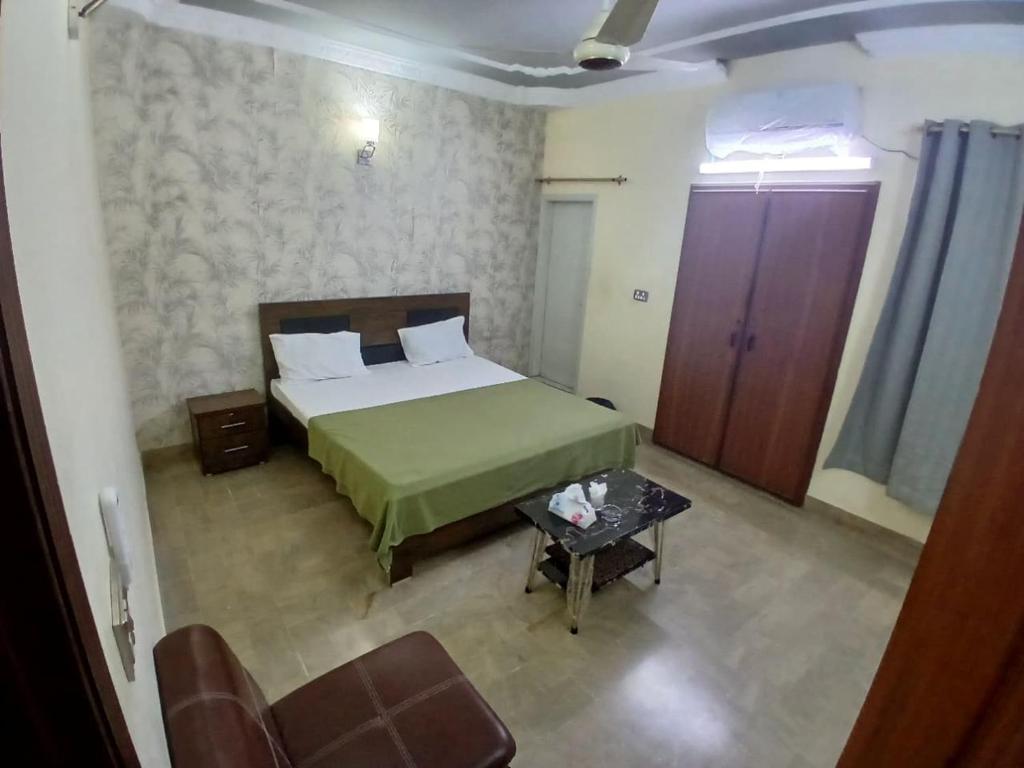 a bedroom with a green bed and a table at Family Inn Guest House in Karachi