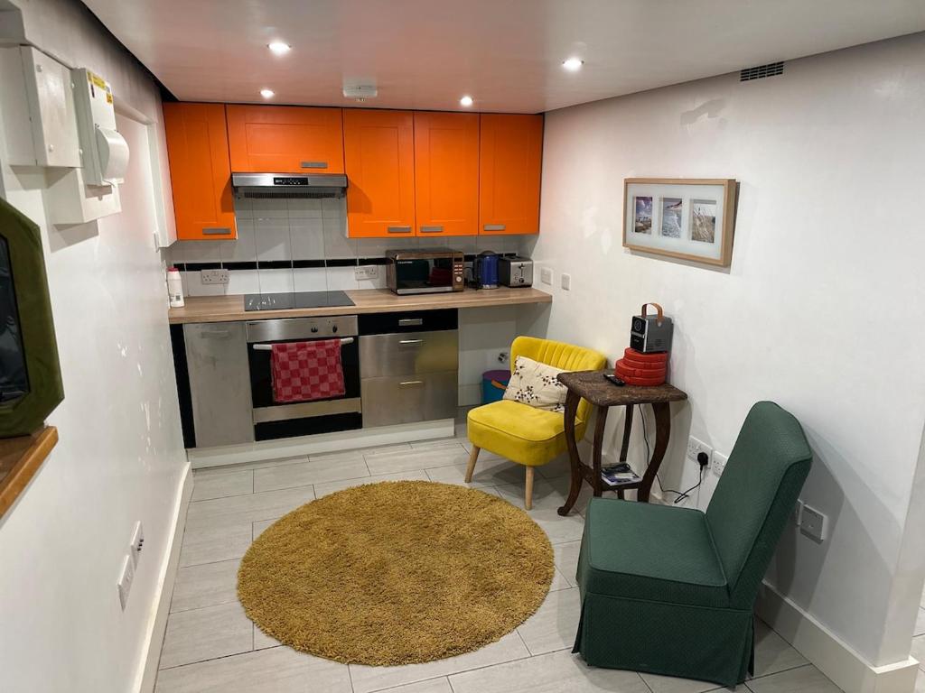 Una cocina con gabinetes naranjas y una mesa y sillas. en Sleek Self-Contained Studio Retreat own entrance, en Dorking