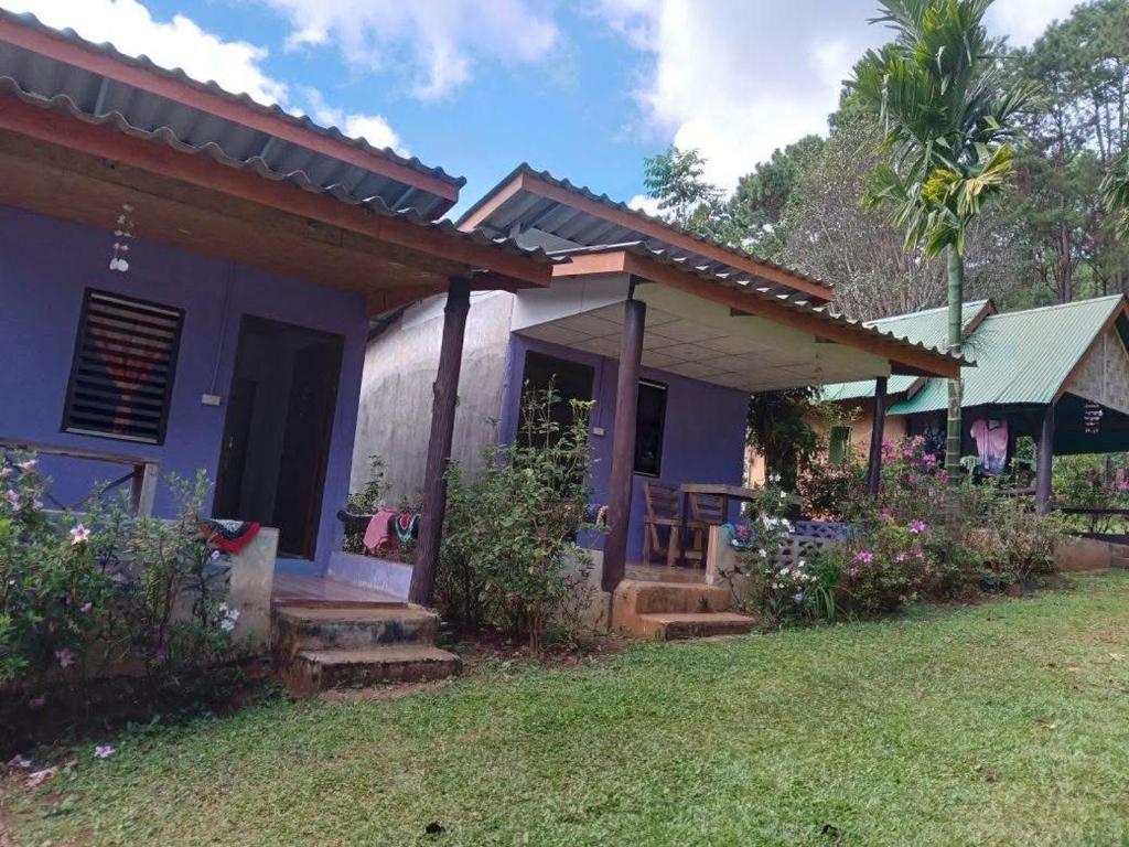 a blue house with a porch and a yard at โบว์ โฮมสเตย์ปางอุ๋ง in Ban Huai Makhuea Som